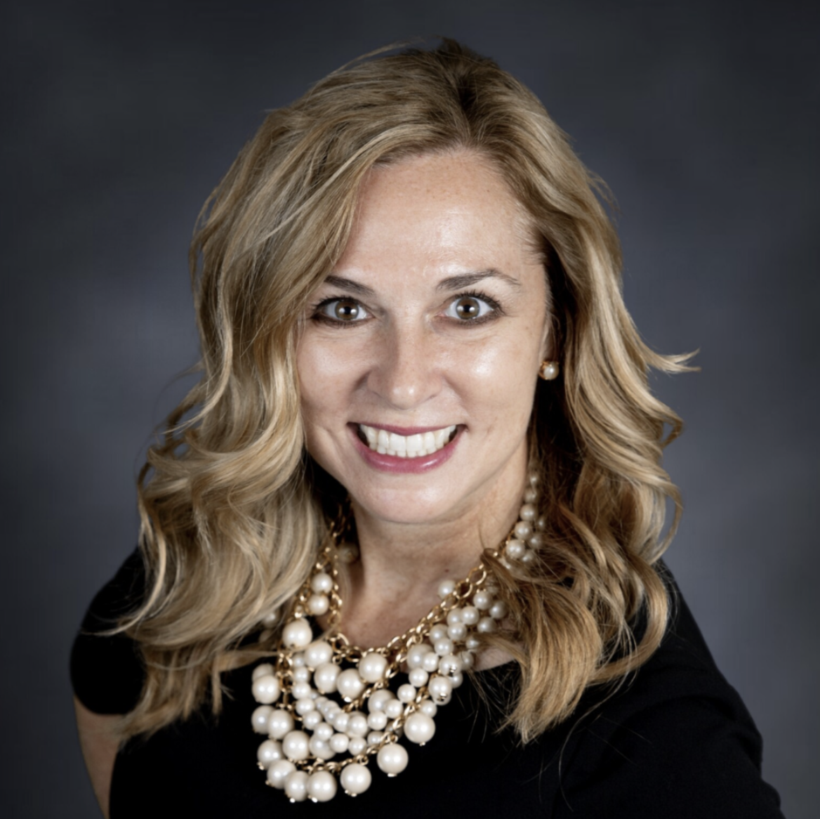 Andrea Davis, CEO of Viticus Group, smiling, wearing a black top and necklace.
