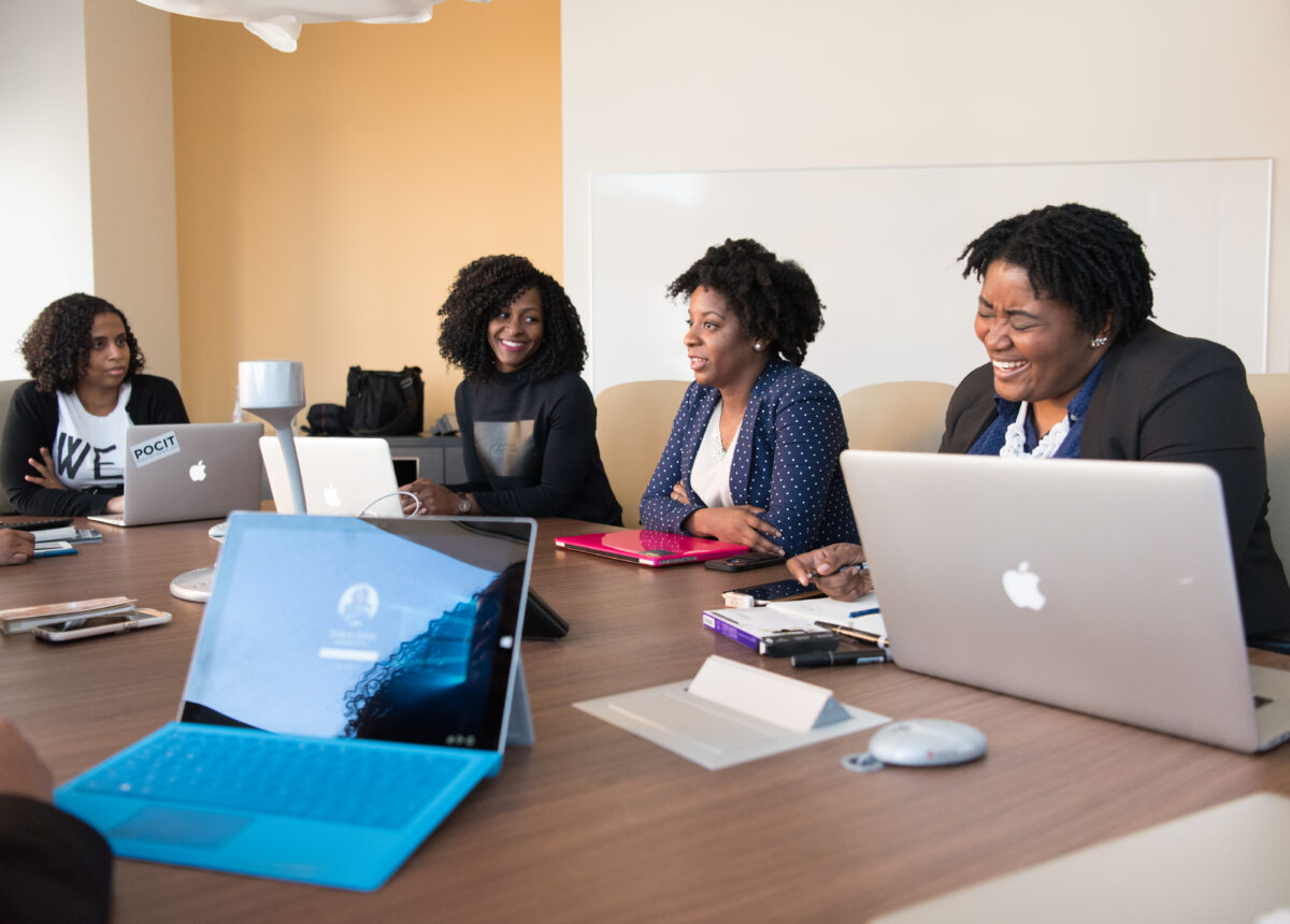 A group of business women work together on laptops in a workspace